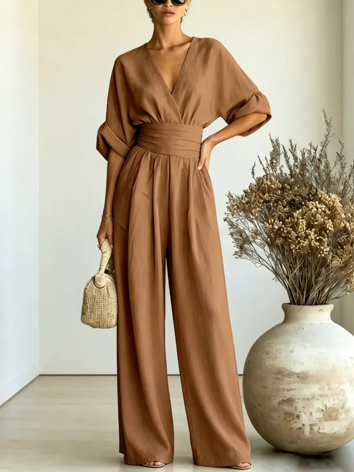 A flowing taupe v-neck wide-leg jumpsuit with a cinched waistband made from lightweight fabric.