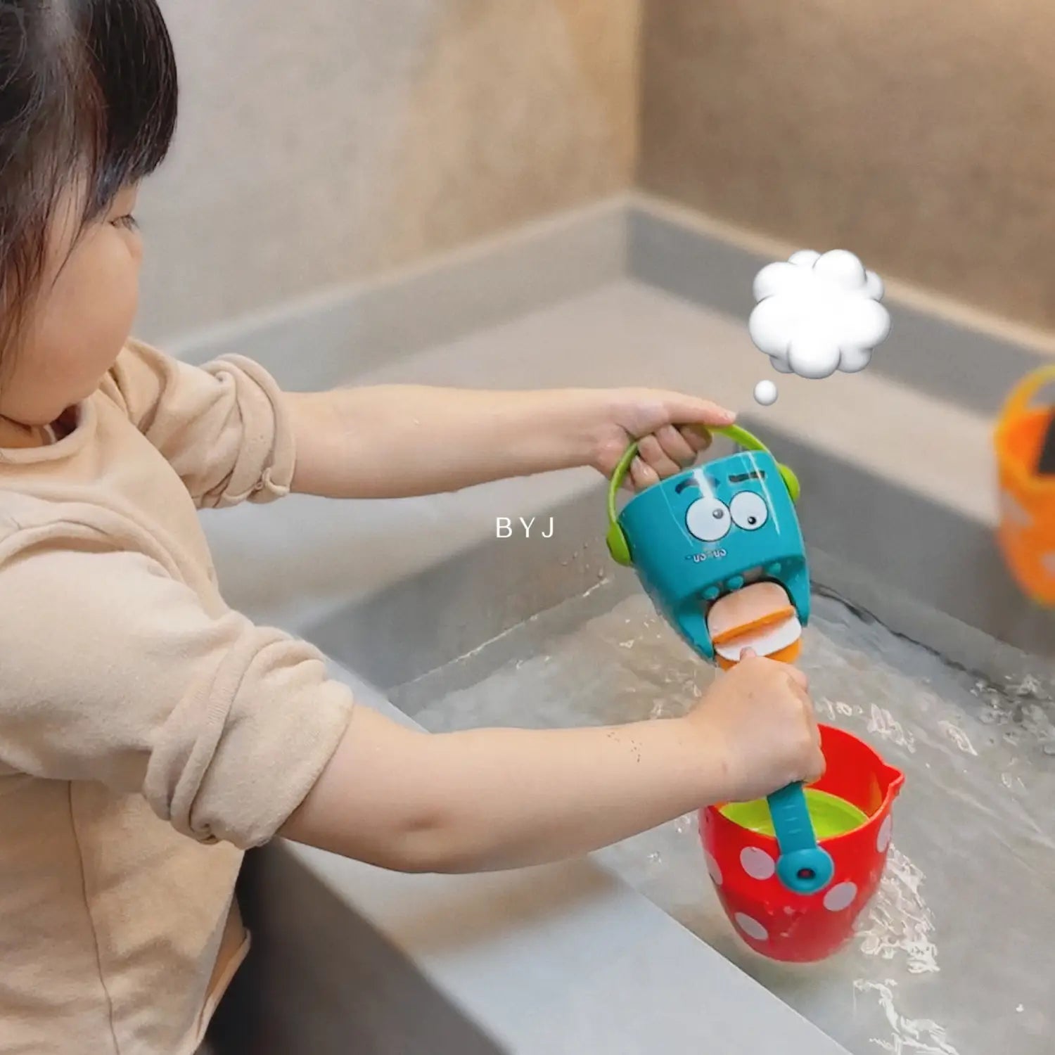 Blauer Kunststoff-Badewannen-Eimer für Babys mit grünem Griff und Cartoon-Gesichtsdesign für ein Wassersprühspielset.