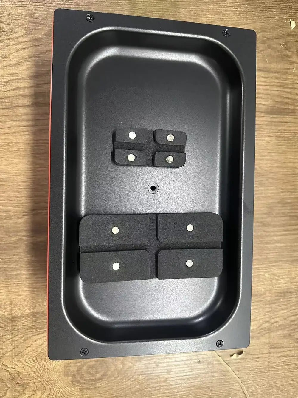 Base de carga magnética rectangular negra con cuatro almohadillas negras de goma, con acentos circulares blancos, diseñada para una máquina de laminación al vacío de película para teléfonos móviles para reducir el costo de envío y mejorar el manejo del teléfono.