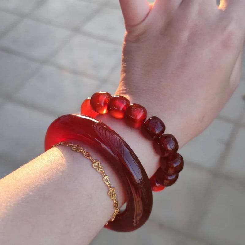 A glossy deep red jade bangle bracelet for women in a classic round style worn on a wrist.