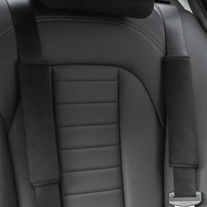Black leather car seat with quilted stitching and padded black and pink plush seat belt covers on shoulder straps.