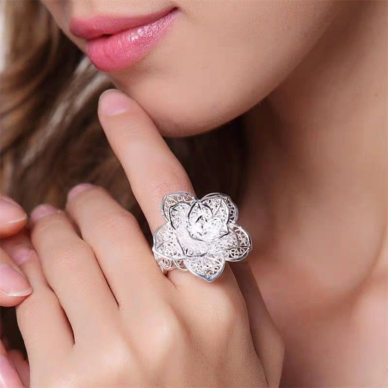 Parure de bijoux floraux en argent sterling comprenant une bague de filigrane délicate en argent, avec un motif de fleur de lotus ajouré complexe et une pierre précieuse centrale scintillante.