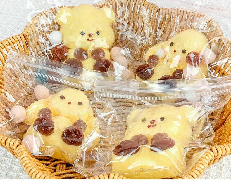 Gelbe Bären-förmige niedliche Tier-Quetschspielzeug-Snacks für sensorische Ablenkung und Stressabbau mit Schokoladen- und pinken Bonbon-Akzenten, einzeln in durchsichtigen Kunststoffen verpackt.