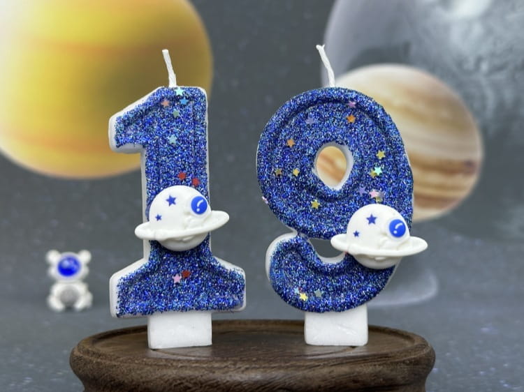 Velas azules con brillo con forma de los números 1 y 9, con figuras de astronauta blancas que presentan ojos azules, utilizadas como adornos para pastel de fiesta planetaria de velas de cumpleaños numerales del espacio.