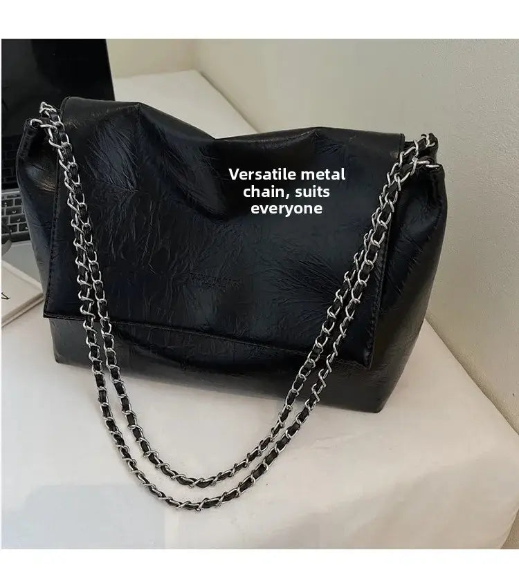 Bolso bandolera negro de piel sintética (PU) con gran capacidad y correa de cadena metálica de tono plateado, diseñado como un bolso bandolera elegante y funcional.