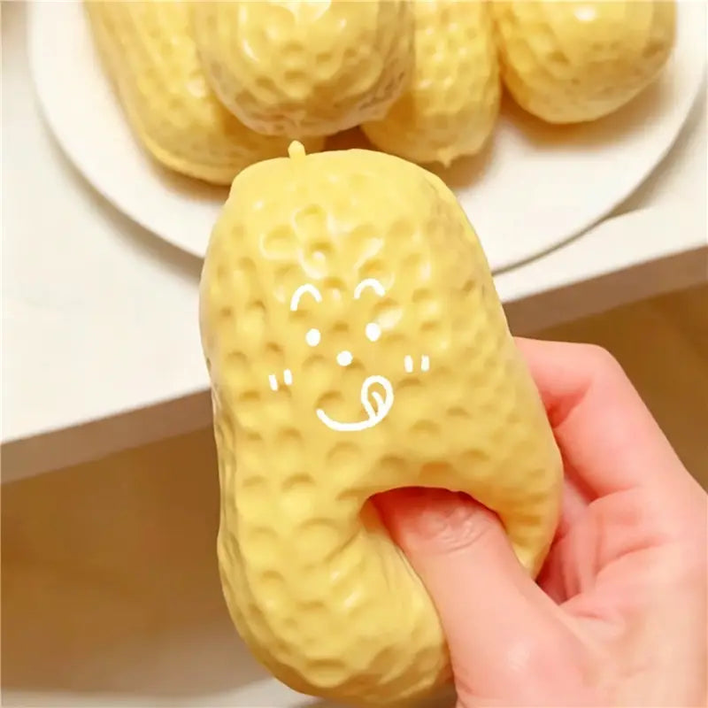 Jouet sensoriel de type balle anti-stress en forme d’arachide, jaune à texture, avec une tête blanche mignonne, conçu pour soulager le stress et favoriser le jeu sensoriel.