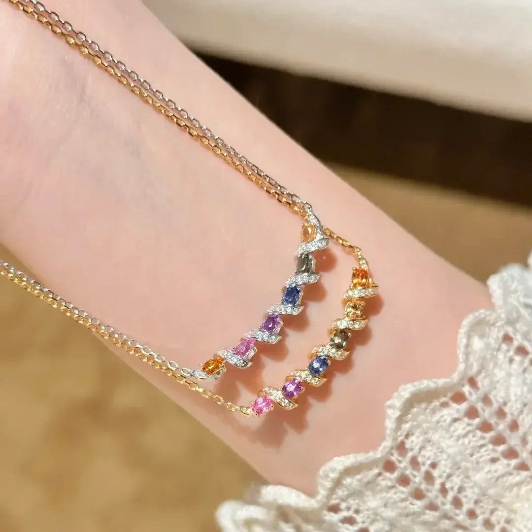 Un collier en argent au design délicat de chaînette torsadée en or, orné de pierres précieuses colorées aux nuances de rose, violet, bleu et orange.
