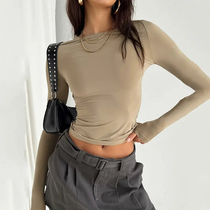 Blusa corta ajustada tipo slim fit beige para mujer, con mangas largas fruncidas, confeccionada con tejido semitransparente elástico de cuello alto.