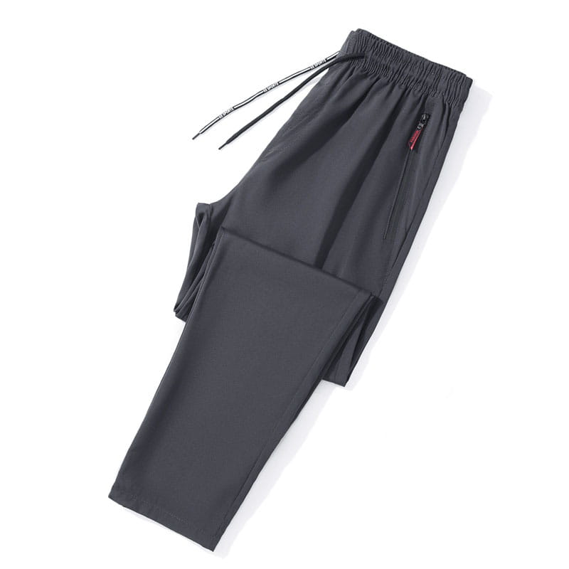 Joggers casuales ajustados para hombre en tejido deportivo gris oscuro, con cintura elástica, cordón y un detalle sutil de cremallera roja en el bolsillo lateral.