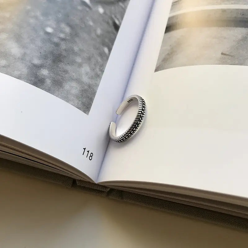 Anillo para el dedo del pie trenzado de plata de ley en color plata, con una banda ajustable texturizada y un patrón detallado de cuentas.