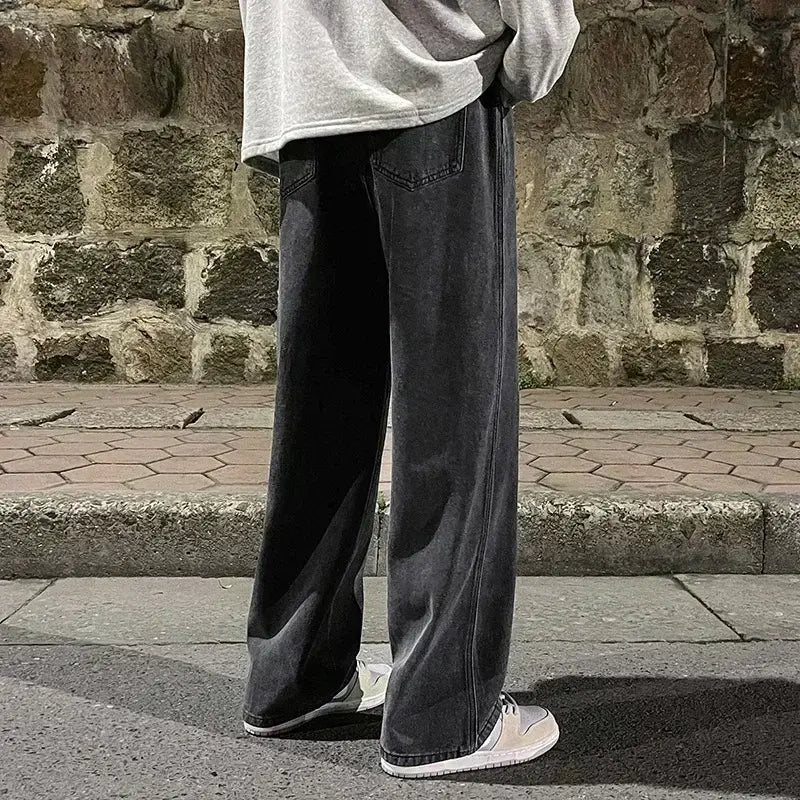 Jeans en denim gris foncé à jambes larges pour hommes, avec un style streetwear coréen ample et des surpiqûres visibles.