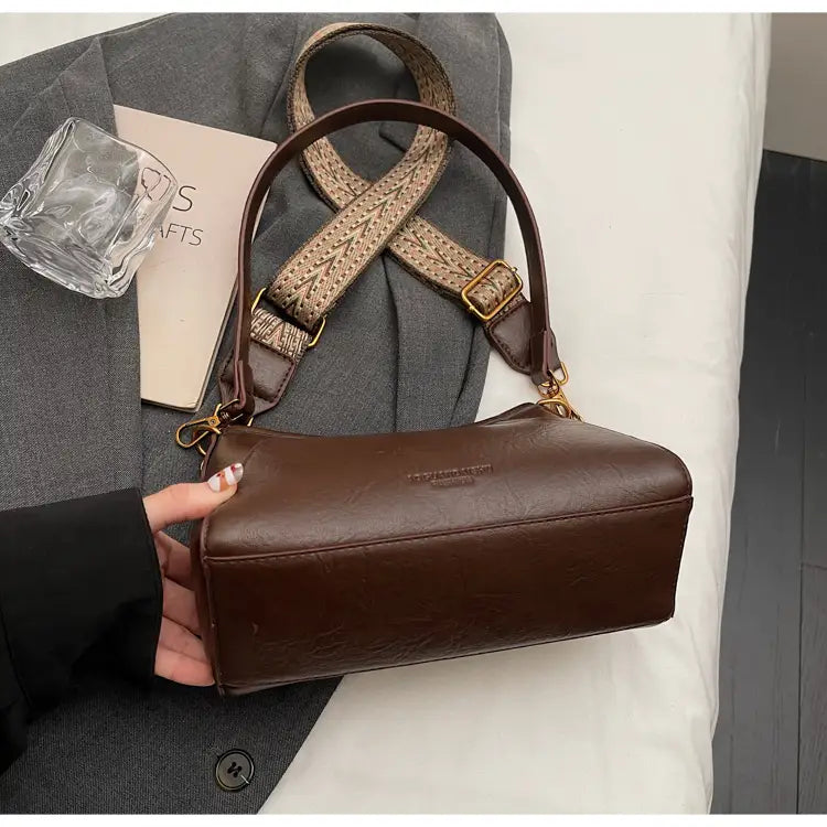 編み込みストラップとゴールドトーンの金具を備えた、女性用ブラウンレザーのクロスボディショルダーバッグ。