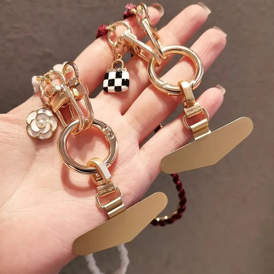Goldfarbener Handy-Handgelenkriemen aus goldfarbener Kette als Anti-Lost-Handylanyard, mit floralen Charms, kariertem Taschen-Anhänger und breiten flachen Clips.