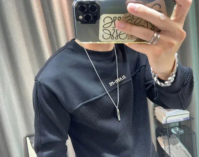 Collier en chaîne argentée avec un pendentif rectangulaire élégant, présenté aux côtés d’un pull-over en maille à empiècement contrastant pour homme, manches longues.
