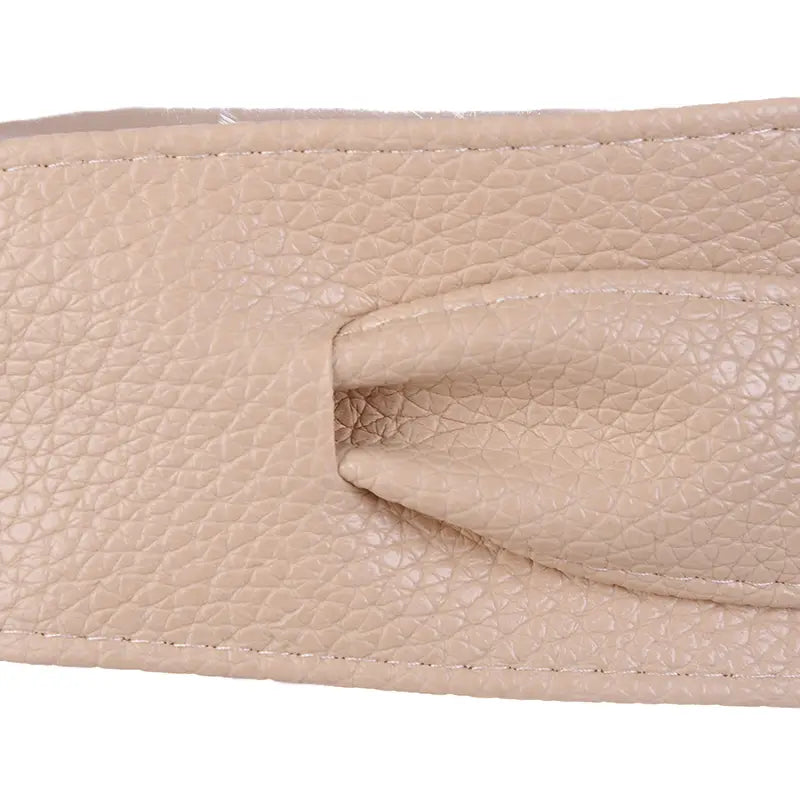 Ceinture large en cuir à nœud papillon noué pour femmes en cuir beige texturé, présentant une finition discrètement grainée et des coutures précises le long des bords.
