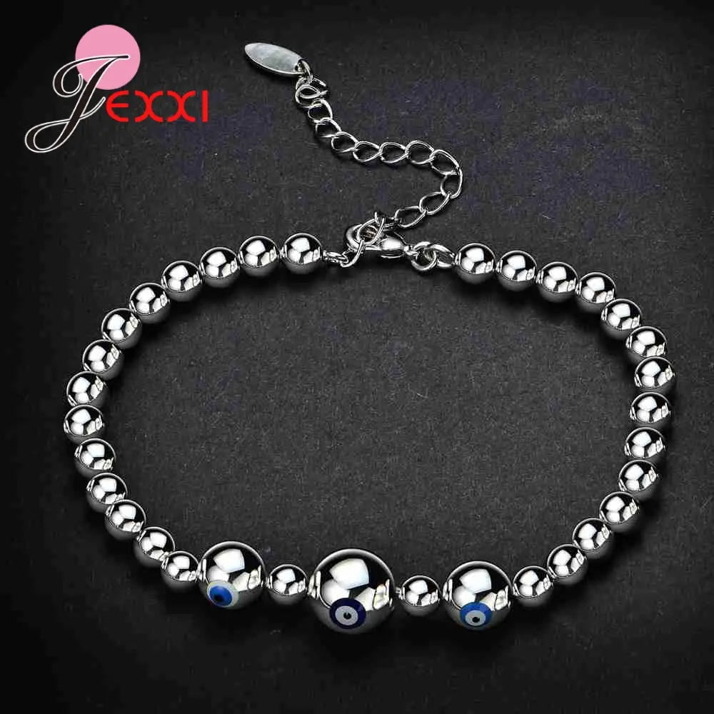 Sterling silver evil eye charm bracelet for women featuring polished silver beads and three prominent evil eye charms with blue centers.