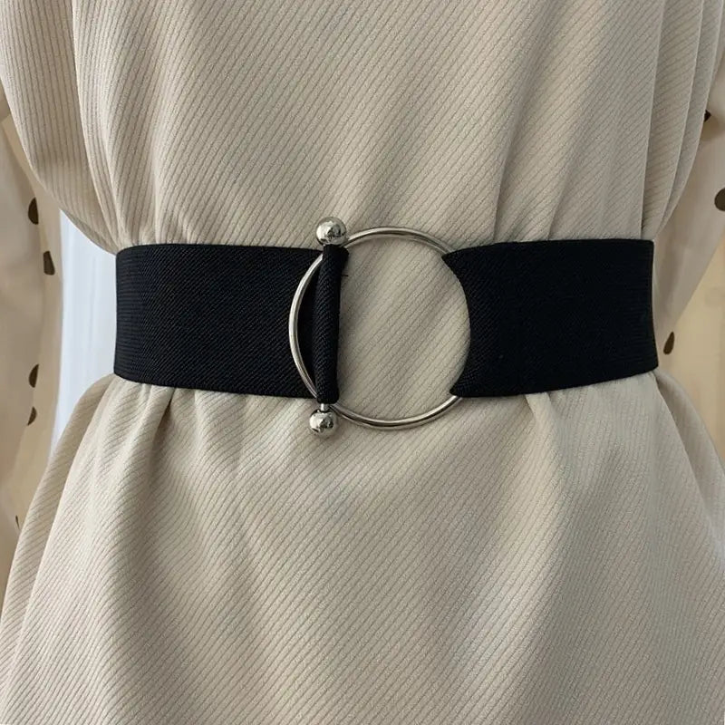 Schwarzer Elastikgürtel für Damen mit runder, eleganter silberfarbener Schnalle und kleinen kugelförmigen Akzenten zur Verwendung als Taillenbund bei Modekleidern.