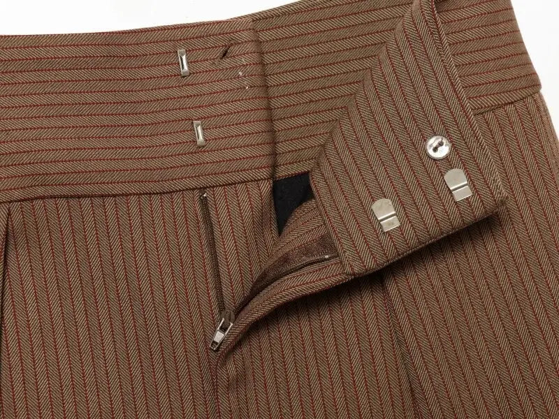 Pantalons taille haute plissés à jambes évasées en tissu marron à motif chevrons, avec de fines surpiqûres rouges discrètes et des boutons métalliques à finition ton argenté.