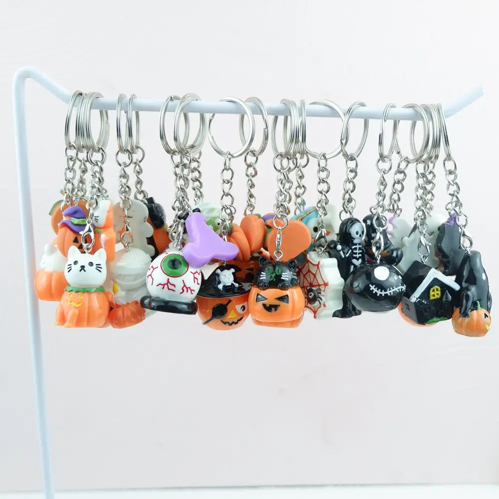 A collection of halloween pumpkin keychain handmade resin jewelry gifts featuring miniature plastic charms in vibrant orange black purple and white.