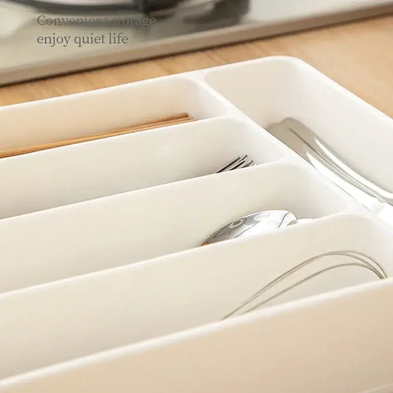 Organisateur de tiroir à couverts en plastique blanc, avec des compartiments distincts pour les fourchettes, les cuillères et les baguettes, pour un usage en cuisine.
