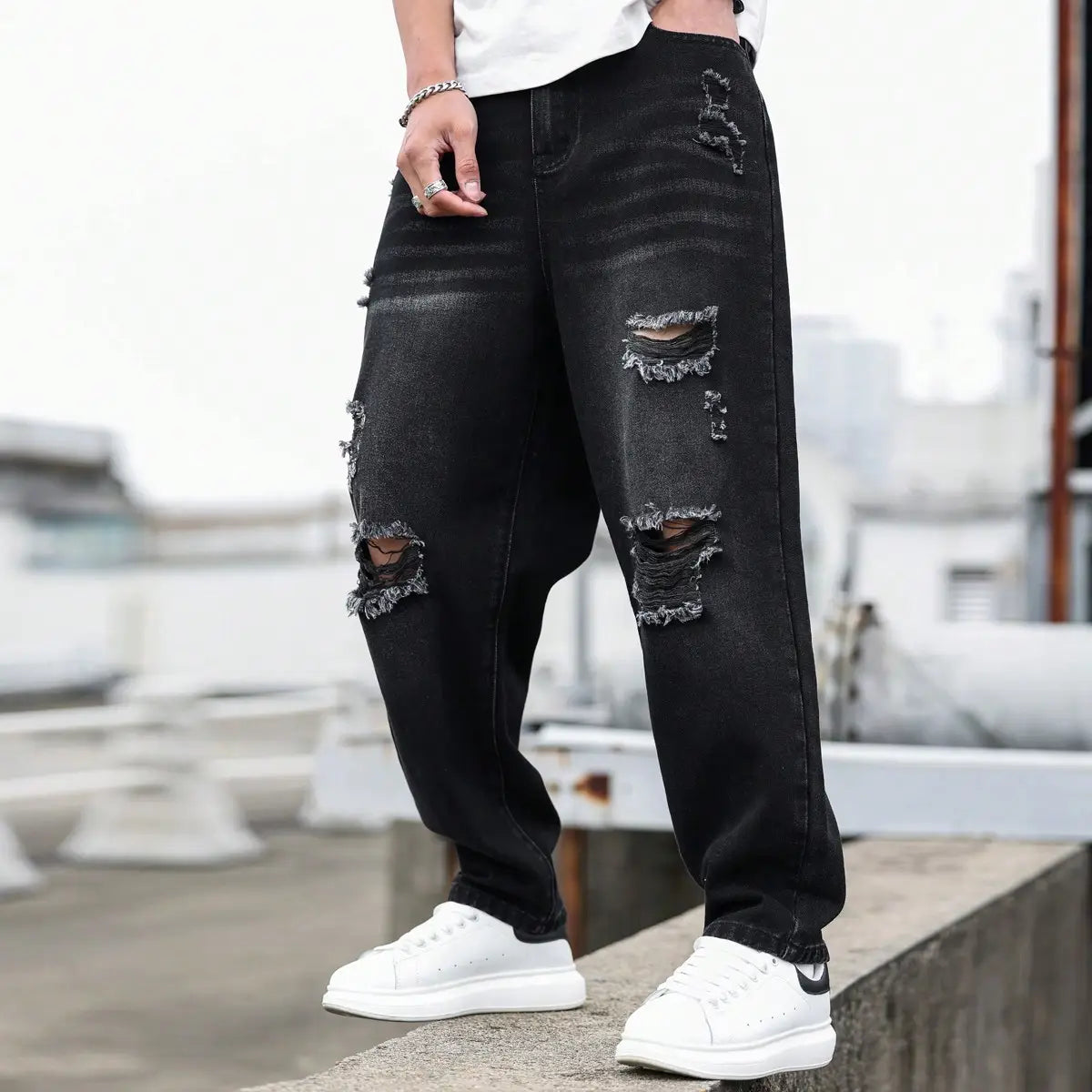 Herren schwarze zerrissene Denim-Haremshosen mit abgenutztem schwarzem Denim, mehreren zerrissenen Patches und ausgefransten Kanten.