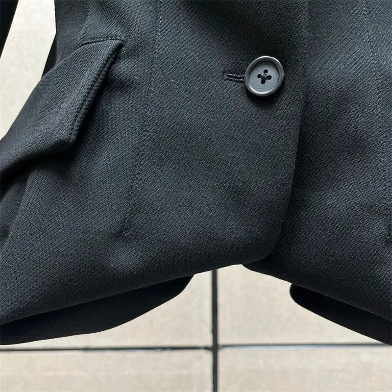 Veste blazer en laine texturée noire avec finition mate et un bouton sombre à quatre trous, associée à une jupe crayon grise taille haute de longueur genou au style Y2K.
