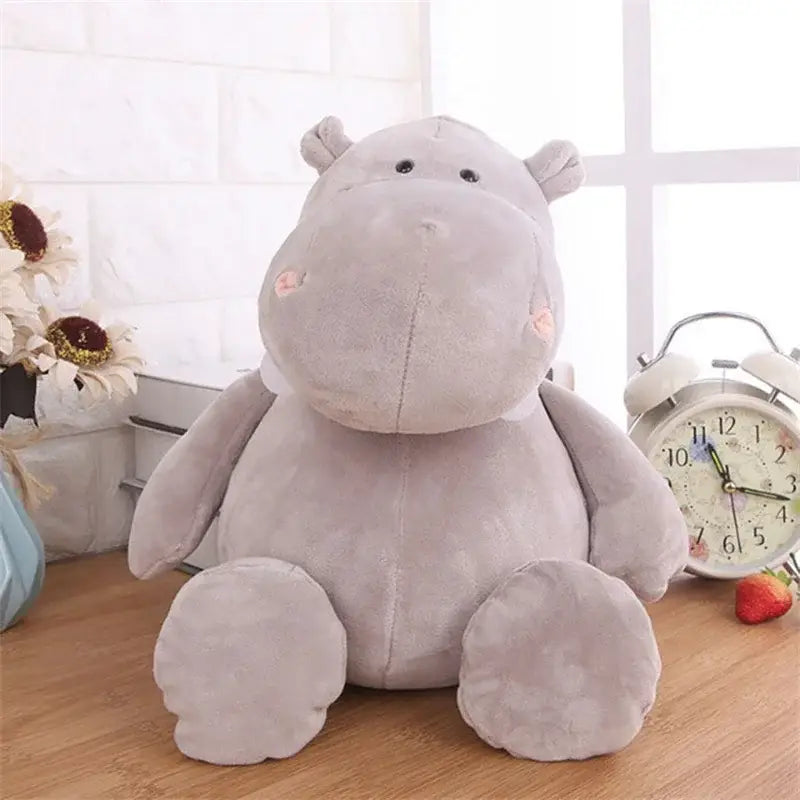 a soft light gray plush hippopotamus toy with black button eyes and pink inner ears in a lion elephant tiger stuffed animal collection