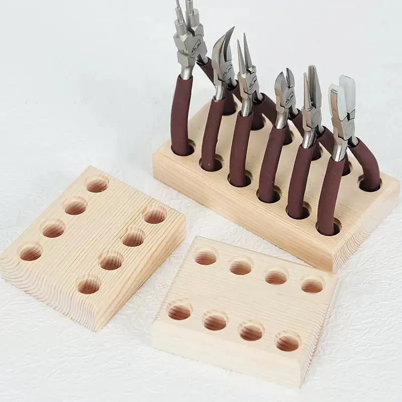 Juego de seis pinzas de joyería con mangos de goma marrón y cabezales metálicos de acabado plateado, dispuestas de forma ordenada en un organizador de herramientas para tablero perforado de madera con soporte de pinzas de color claro.