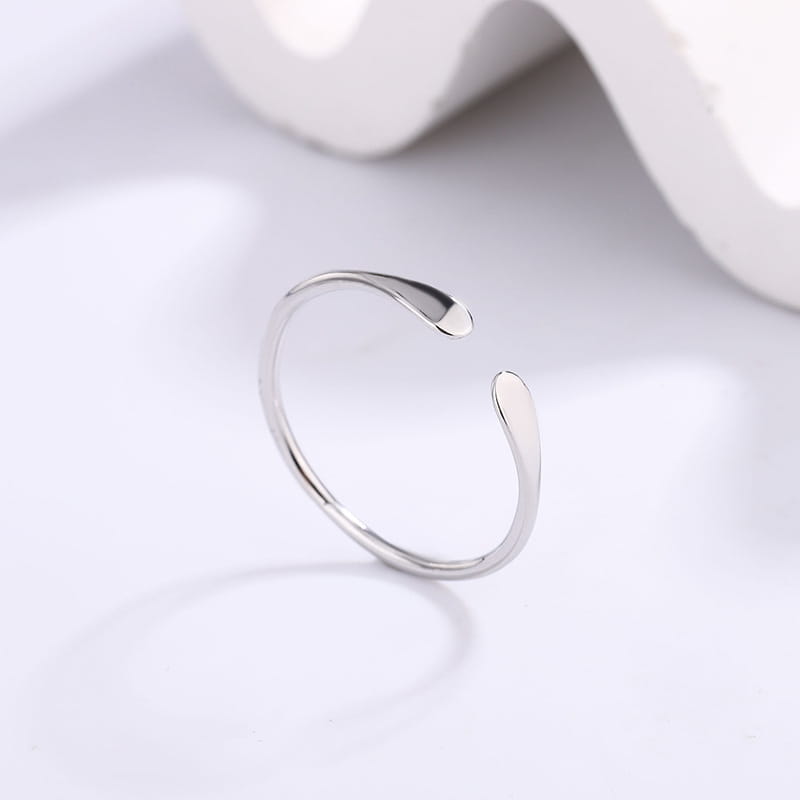 Un anillo apilable con forma de gota de plata de ley que presenta un diseño abierto en plata, con un estilo minimalista y elegante y un acabado pulido suave.