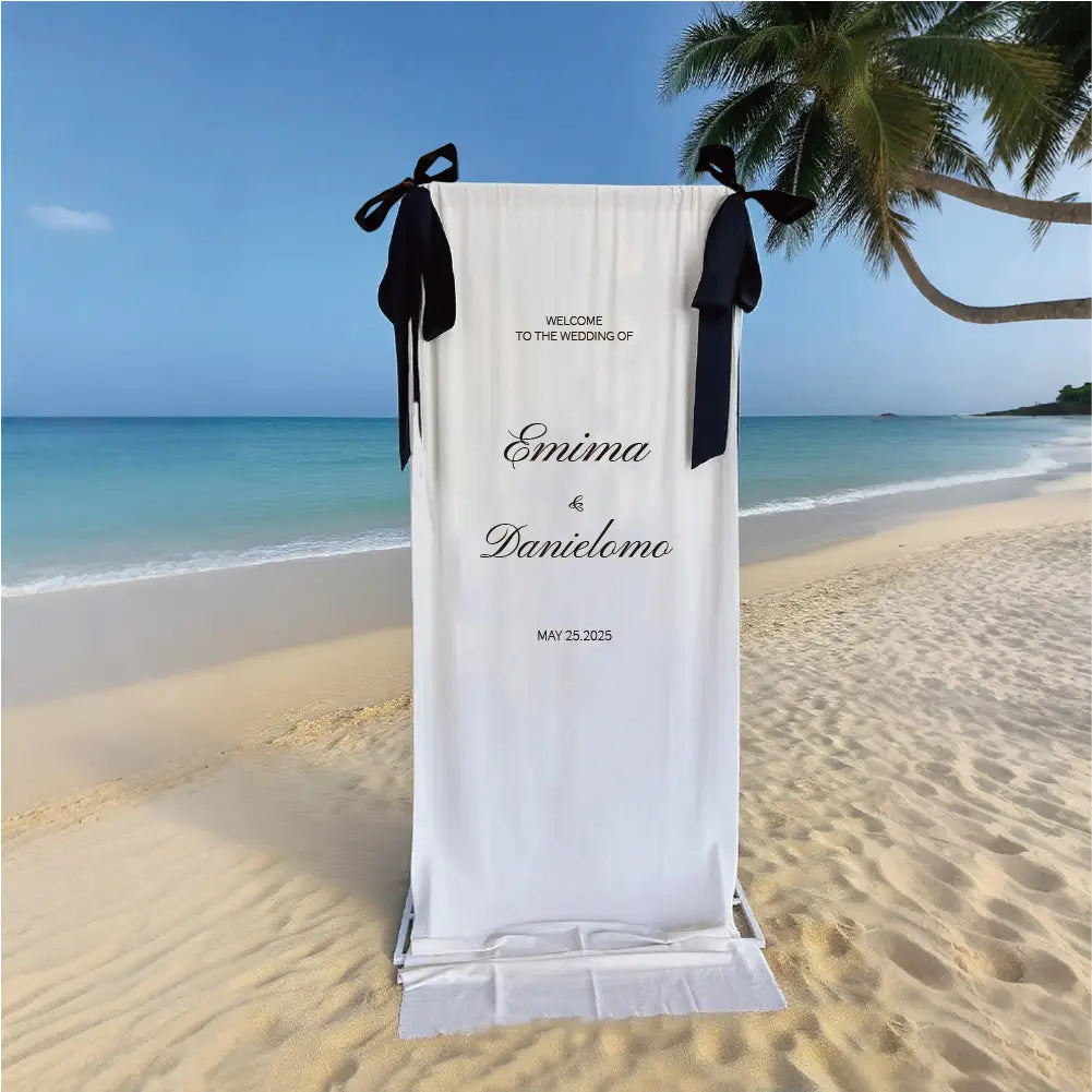 panneau de bienvenue de mariage personnalisé en tissu avec un fond en tissu blanc, des rubans en satin noir et un texte cursif élégant.