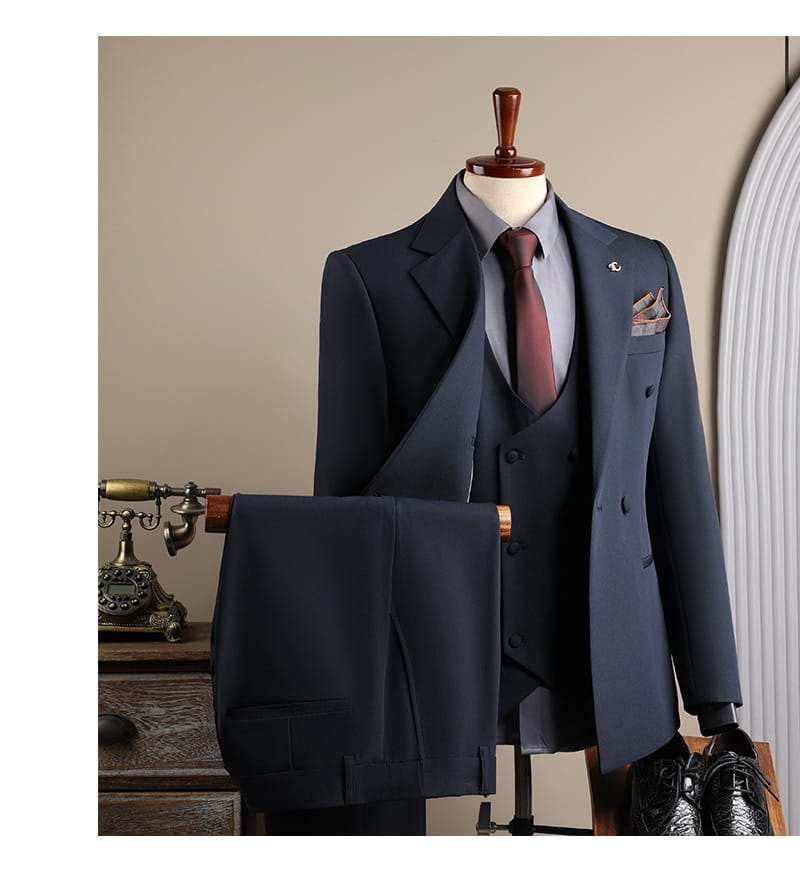 Ensemble costume d’affaires pour homme bleu marine slim fit en trois pièces, avec veste à revers cranté double boutonnage et gilet assorti, présenté sur un mannequin en bois, idéal pour les occasions d’affaires en mode masculine et de soirées décontractées.