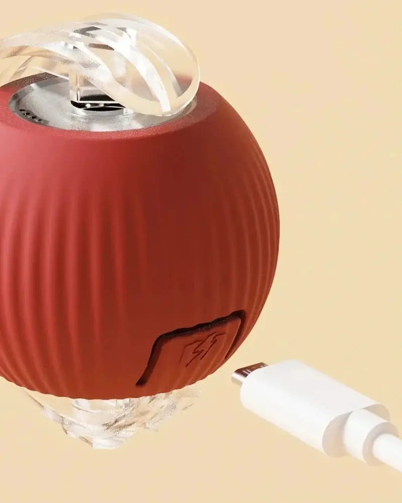 Red spherical smart ball pet toy with ribbed silicone texture, transparent plastic top, usb-c charging port, and indicator light stays for interactive automatic rolling.