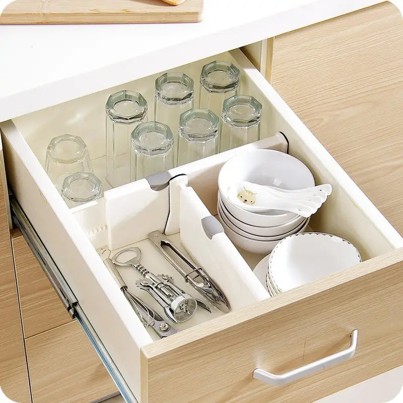 Cloison de tiroir en plastique blanc avec des clips gris comportant des compartiments réglables permettant d’organiser des bols, des assiettes et des ustensiles en vue du rangement dans une séparation de stockage.