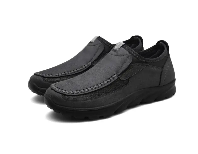 Mocassins homme décontractés à enfiler en noir, avec dessus effet daim et semelle en caoutchouc présentée depuis le côté arrière