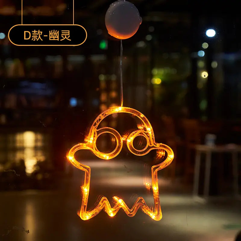 Orange led light-up ghost-shaped battery operated Halloween window hanging decor with suction cup top for easy attachment.