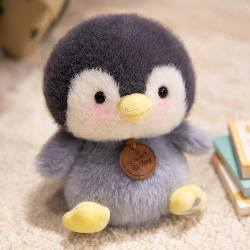 cute plush penguin with soft gray and white fur and yellow beak and feet wearing a brown wooden tag as part of sitting animals red panda fox sloth plush toys collection.