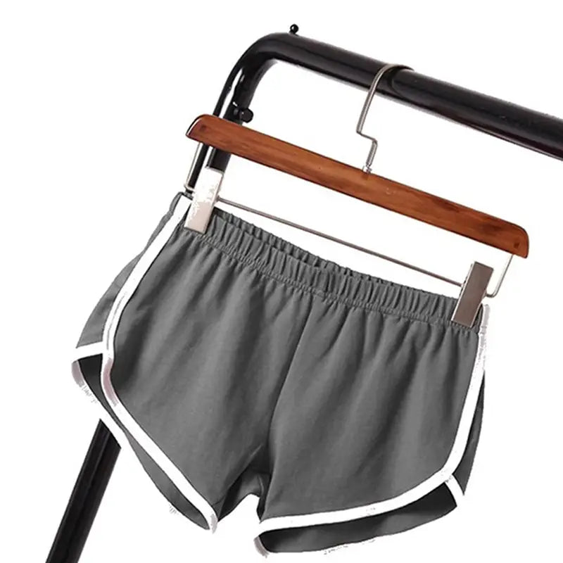 gray sports shorts women with white trim and elastic waist hanging on a wooden hanger suitable for casual athletic wear