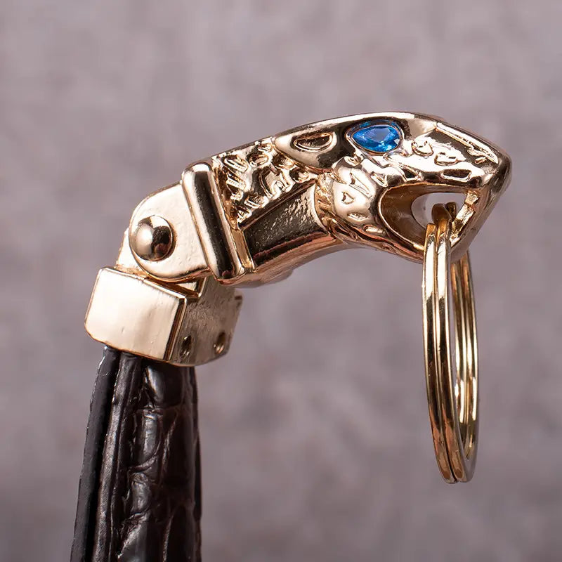 Leather tiger head keychain featuring a gold-toned jaguar head with a blue gemstone eye attached to a black leather strap for luxury car key ring use.