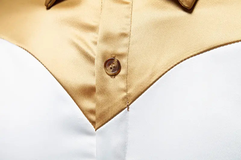Ein goldfarbener Knopf mit leichtem Schimmer, der in den satinähnlichen Stoff eines Herrenhemds mit goldfarbenem Besatz aus Satin eingelassen ist.