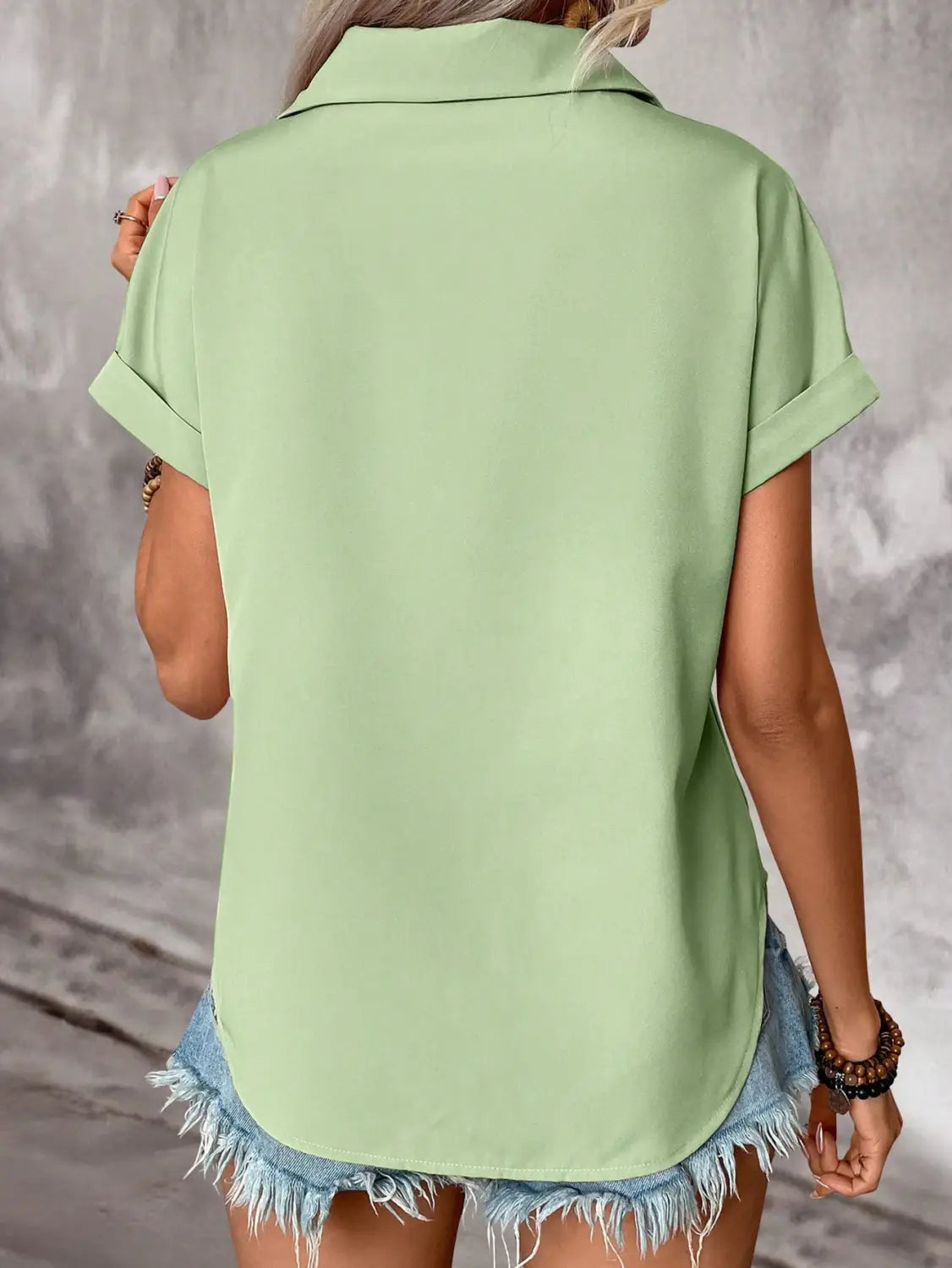 Light green short sleeve button up blouse for women with rolled cuffs and collar highlighting the sleeve length.