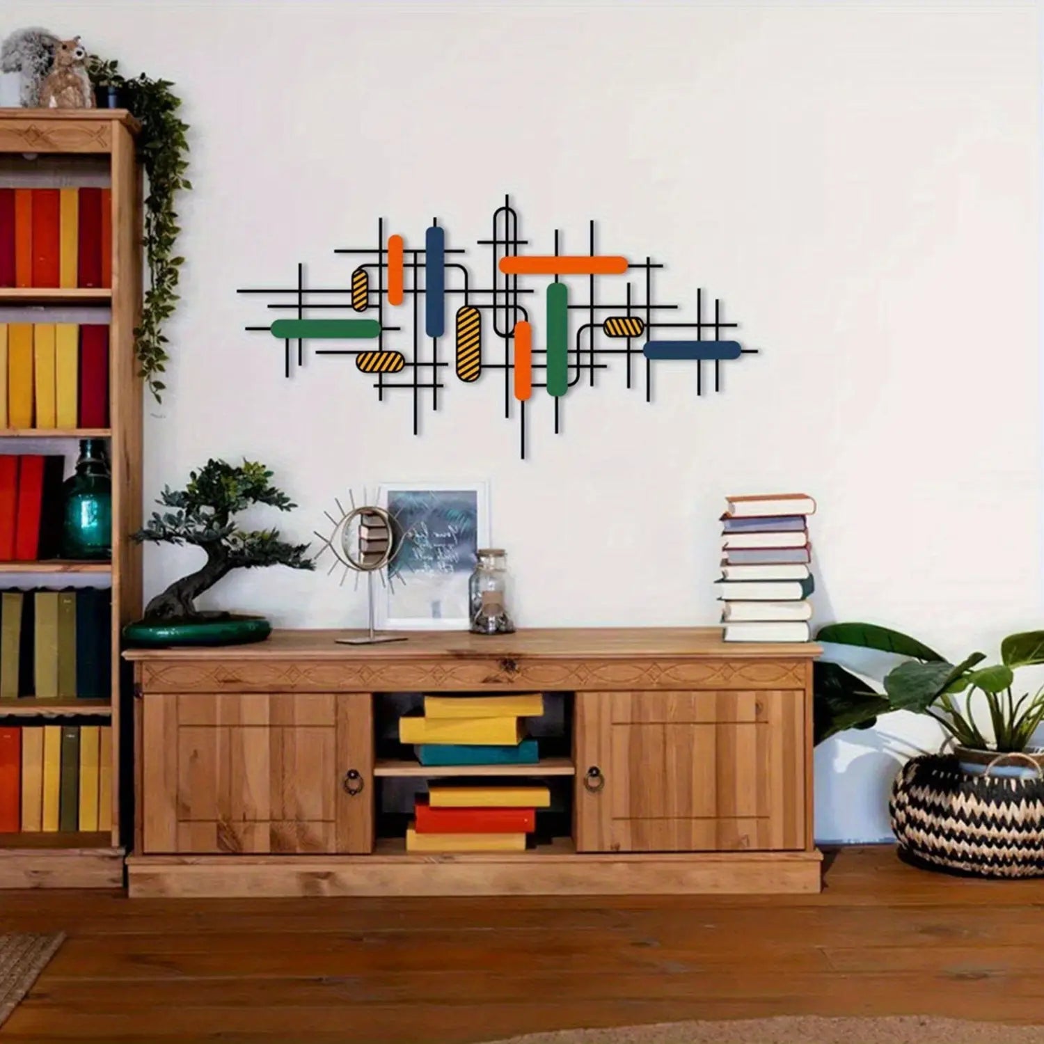 A modern colorful geometric metal wall art piece featuring black metal rods intersected with vibrant orange green blue and yellow rectangular and cylindrical elements for unique wall decor.