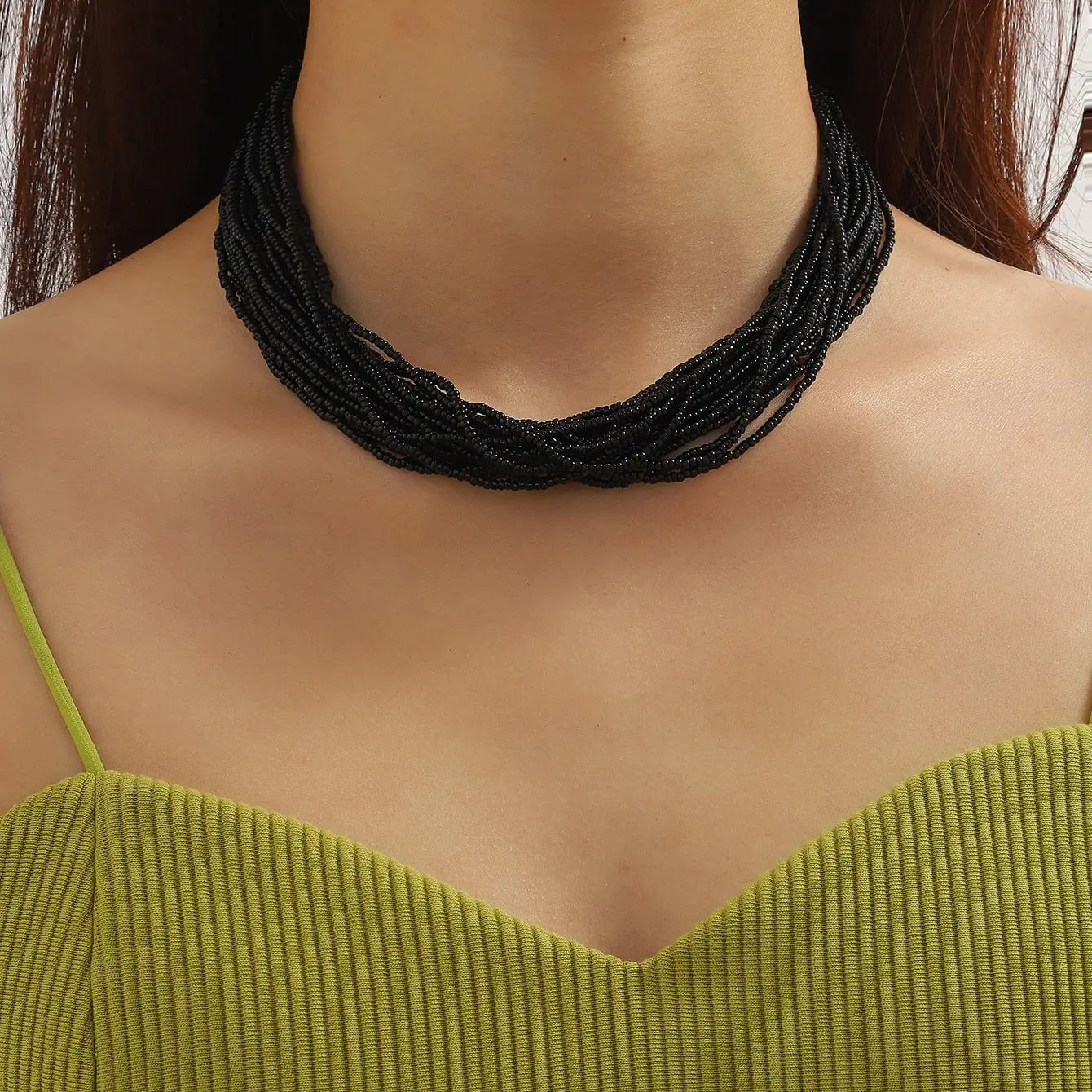 Collier ras du cou boho à plusieurs rangs avec perles noires, comportant plusieurs brins tressés, conçu pour une utilisation élégante comme accessoire.
