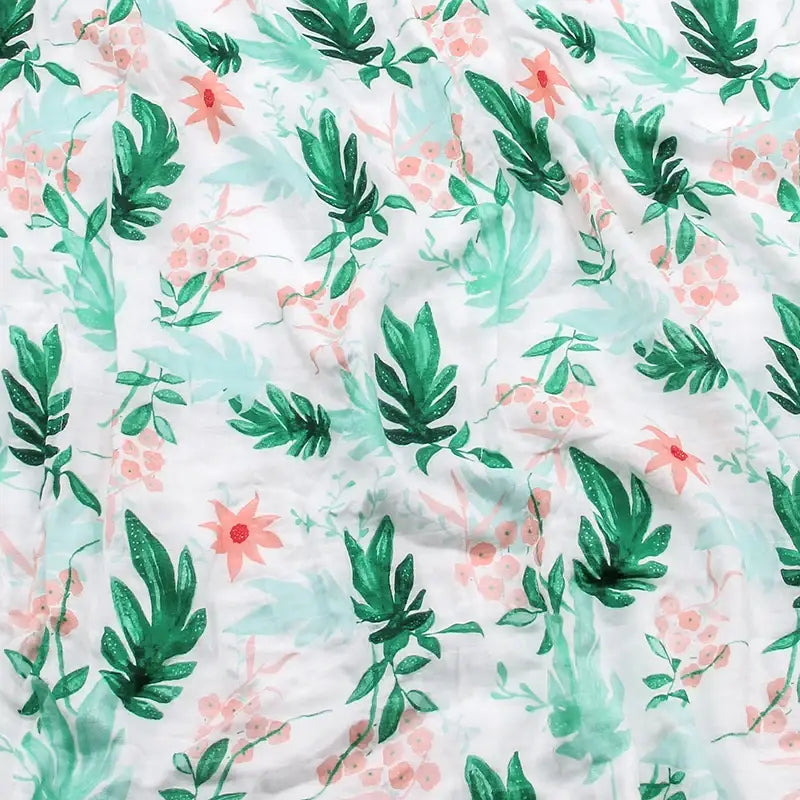 Weiße Bambus-Baumwoll-Decke für Babys (Swaddle) mit floralen Motiven, mit einem lebendigen tropischen Druck aus grünen Blättern und rosa Blumen.