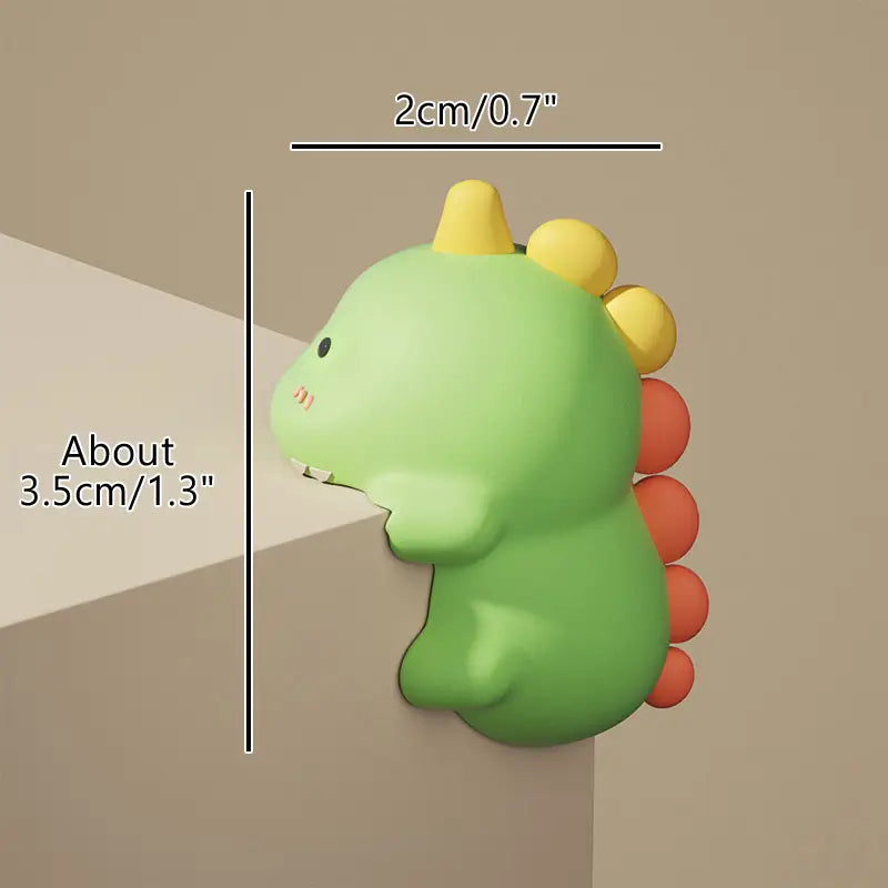 grüner Eckschutz für den Tisch in Dino-Form mit gelben Stacheln und orangefarbenen Segmenten für den Schwanz zur Sicherheit von Babys.