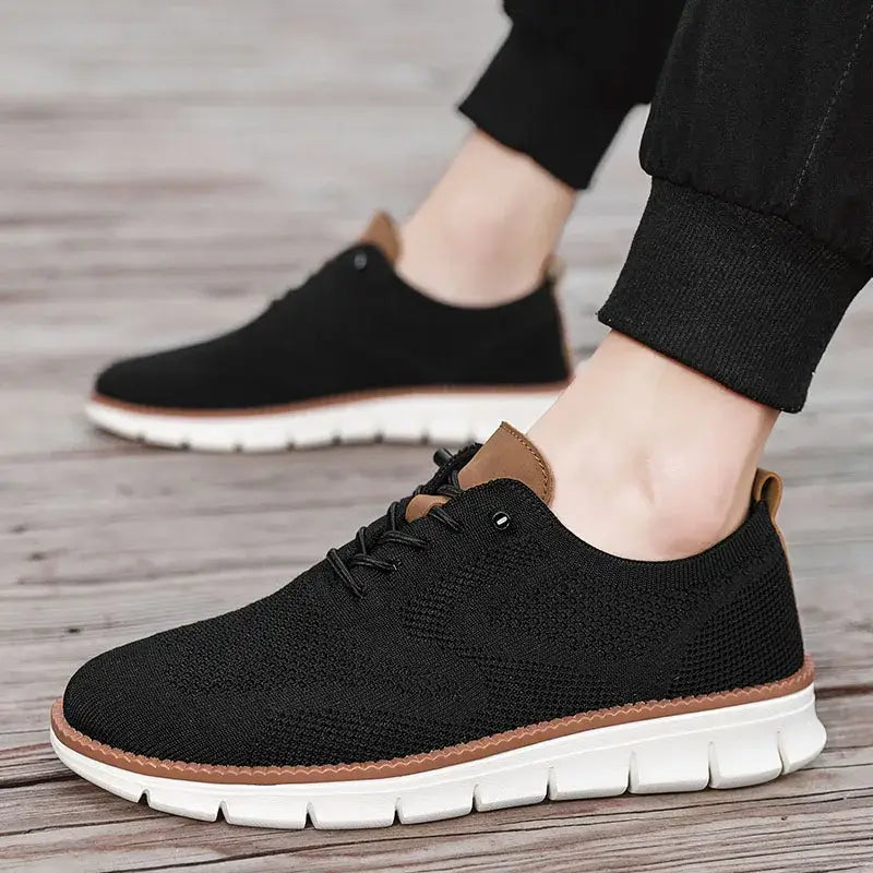 Chaussures derby brogue décontractées en maille pour hommes, de couleur noire, avec un design de laçage en maille, des accents en cuir tan et une semelle en caoutchouc blanc.