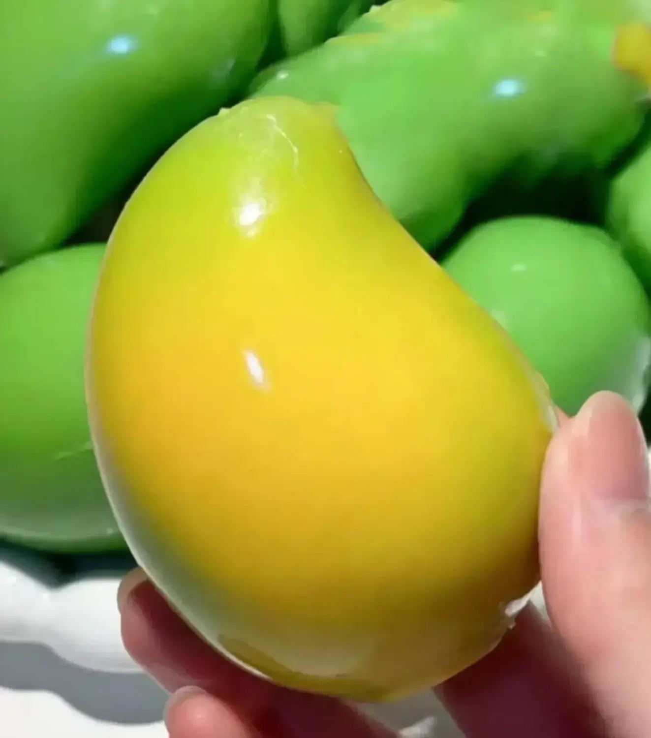 un jouet à mâcher et à malaxer en forme de fromage, vert jaune brillant, conçu pour soulager le stress, texture souple et molle, avec une surface lisse légèrement incurvée tenue dans la main pour apaiser le stress lié au jouet.