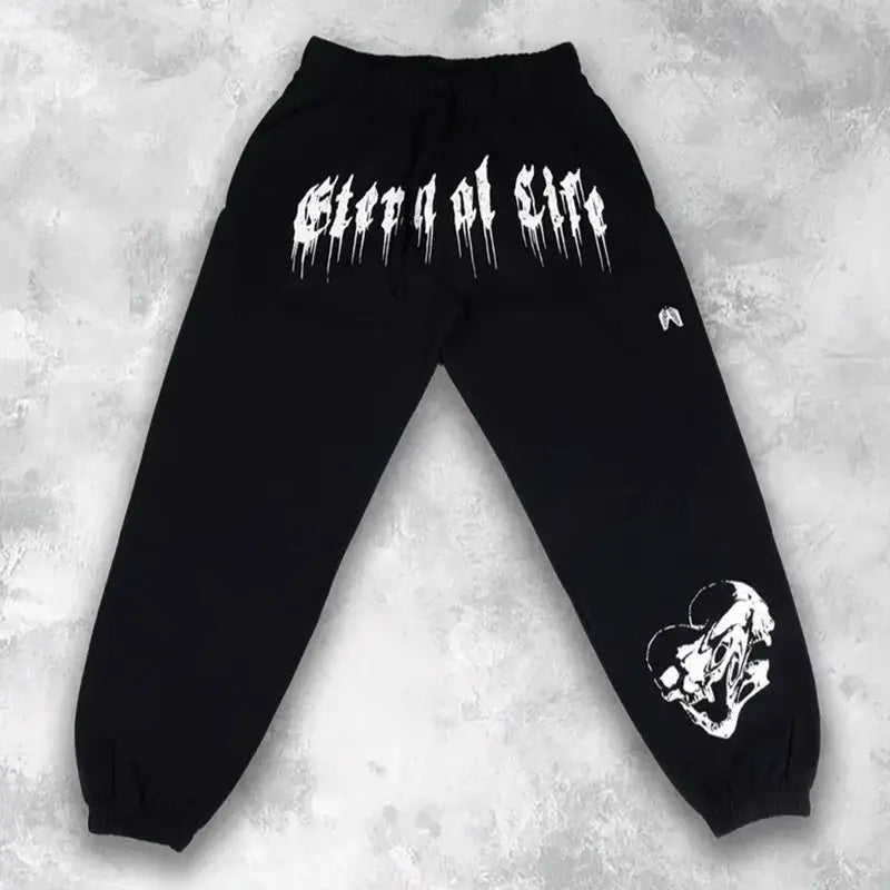 Survêtements d’entraînement pour hommes noirs, vêtements d’entraînement en mélange de coton, avec un texte style graffiti blanc qui s’écoule au dos et un graphisme de crâne sur la partie inférieure de la jambe visible depuis l’arrière.