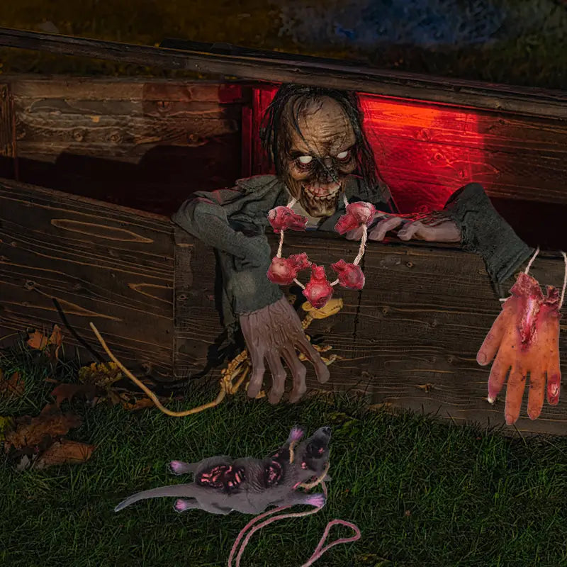 Un personnage de zombie effrayant, avec un visage grisâtre en décomposition et des vêtements verts en lambeaux émergeant d’un cercueil en bois, tenant un collier de cœurs sanglants dans l’ensemble de fausses parties du corps suspendues d’Halloween sanglantes