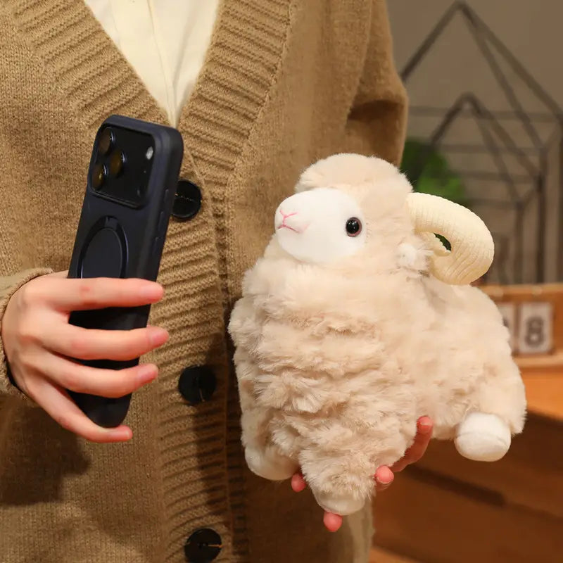 Plüschschaf-Geschmacktier im niedlichen Kawaii-Weichpuppen-Design mit einem flauschigen Rammler in Cremefarbe, mit weich strukturierter Oberfläche, schwarzen Knopfaugen, rosafarbener Nase und Hufen