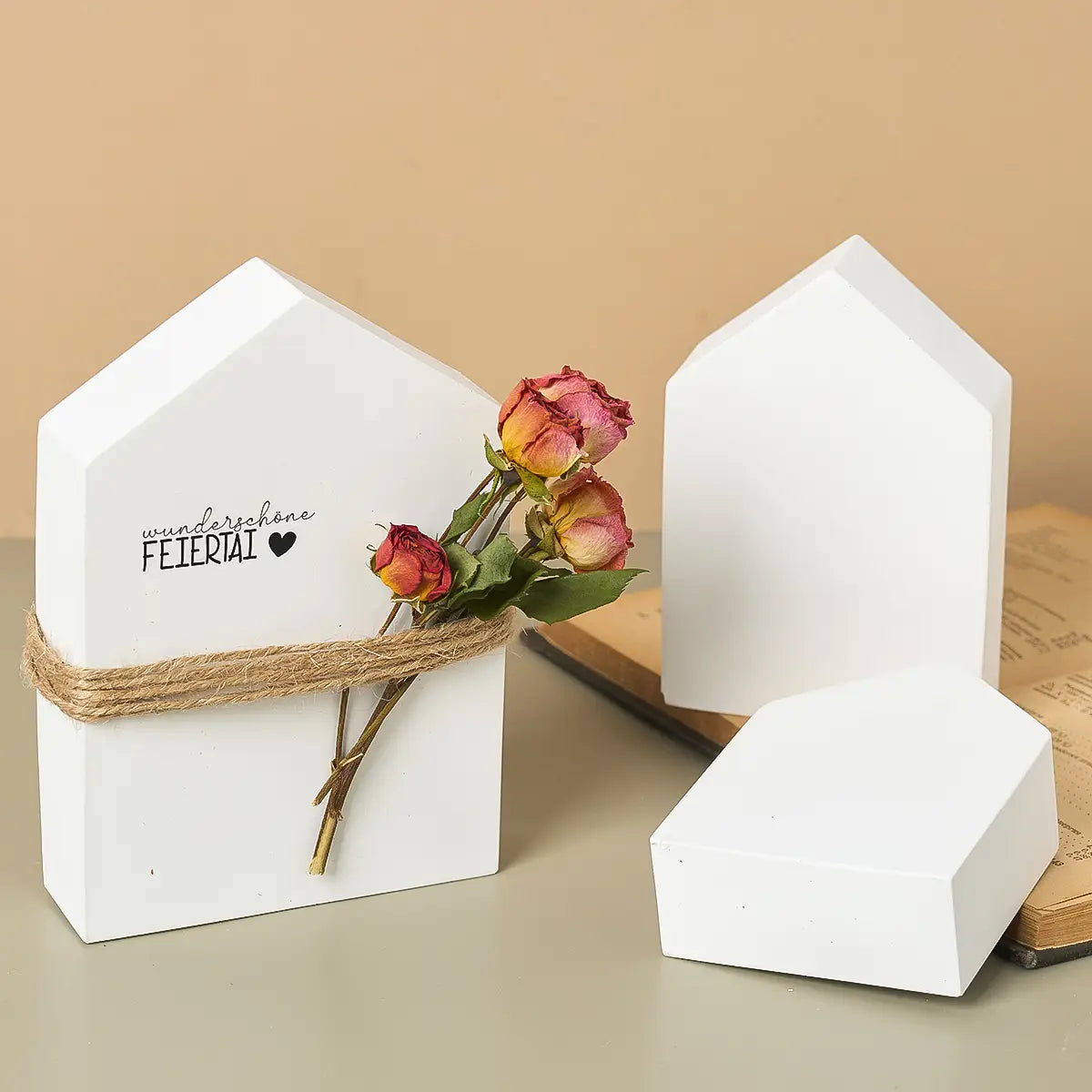 weiße Keramik-Buchstützen in Hausform, umwickelt mit rustikalem Bast und verziert mit getrockneten Rosen für DIY-Bastelarbeiten mit Gipsformguss-Pulver